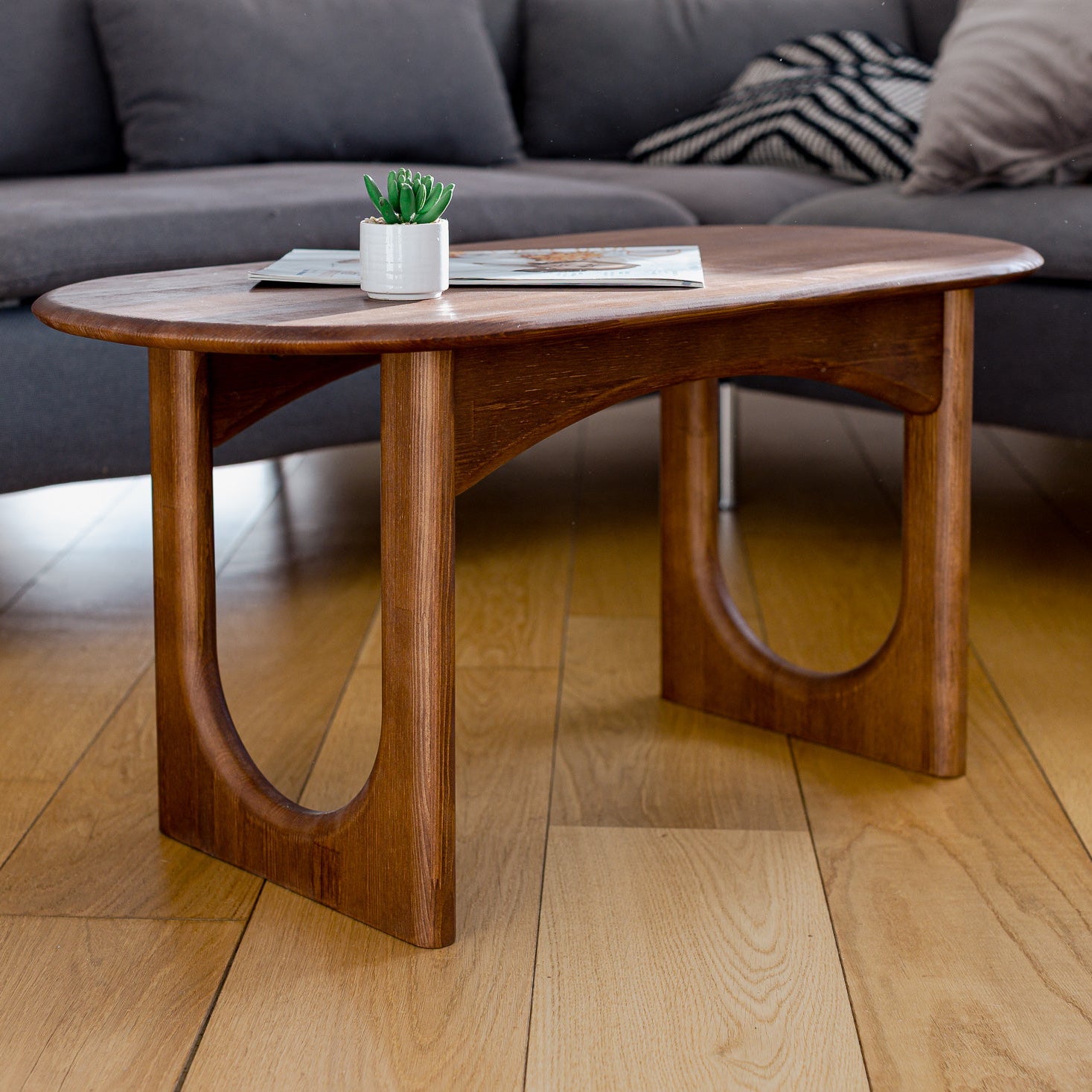 Wooden coffee table with a plant and books in a living room setting