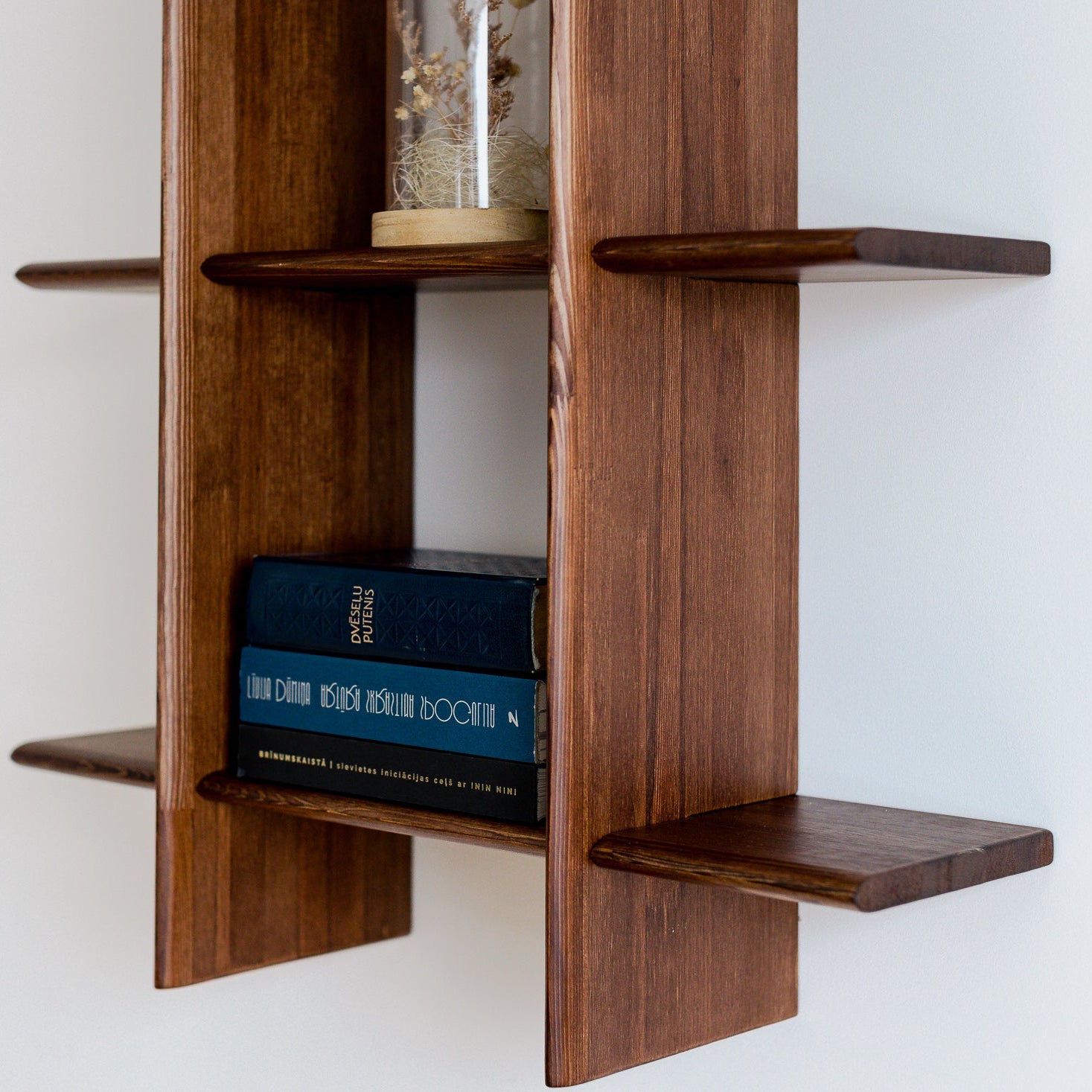 Wooden shelf with books against a white wall